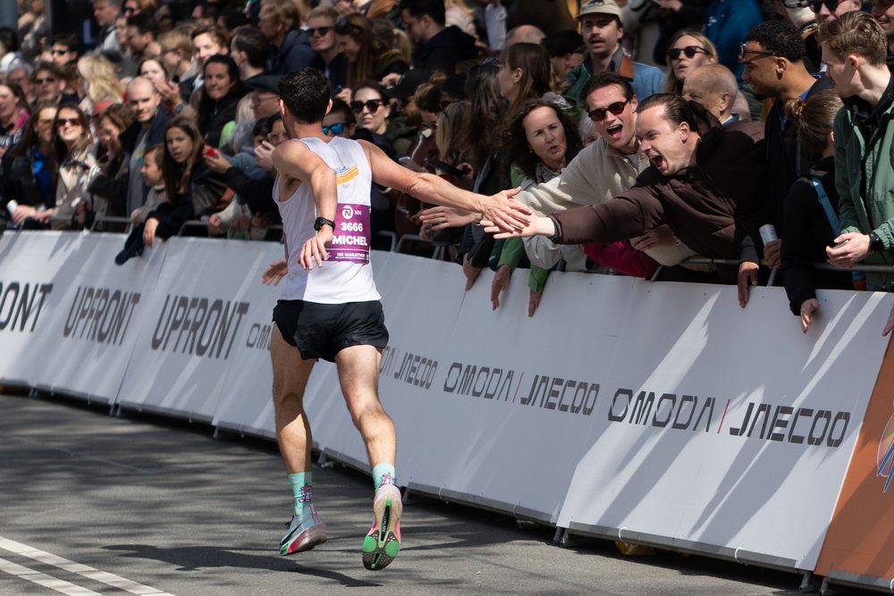 Marathonloper geeft high fives aan het publiek langs de afzetting
